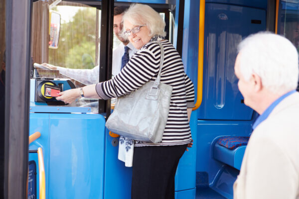 Elderly Senior Couple Boarding Public Bus And Using Pass